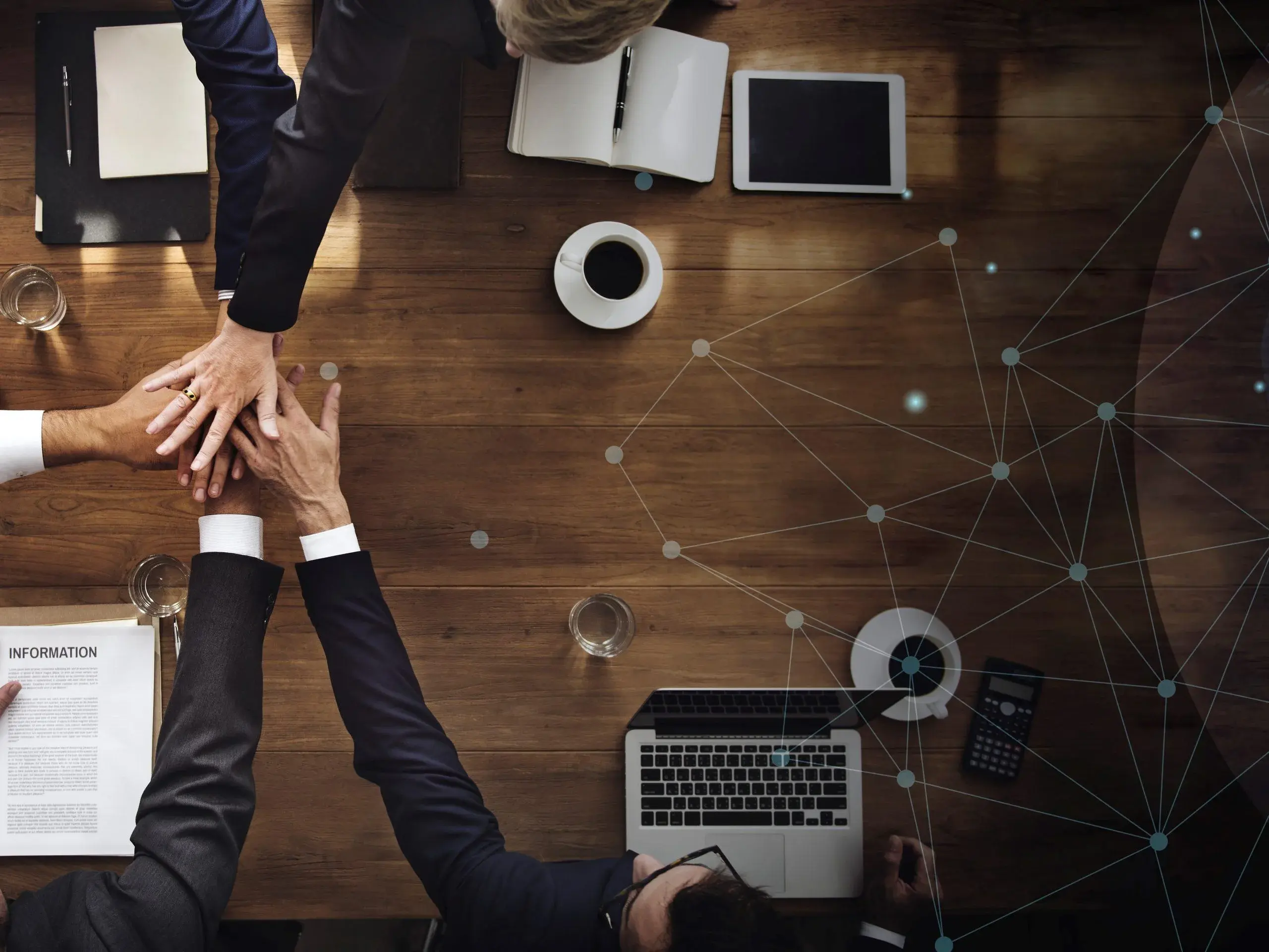 RixDigi team joining hands over a desk with laptops, representing collaboration on AI projects